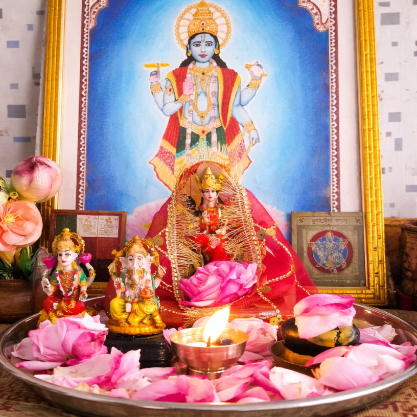 Hindu home temple with Lord Vishnu painting, Goddess Lakshmi idol, Lord Ganesha statue, diya lamp and rose petals during puja